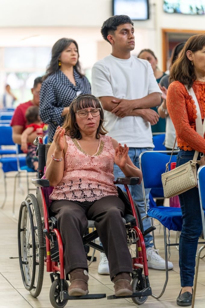 A woman in a wheelchair prays alongside others during a church service in Ciudad de México.